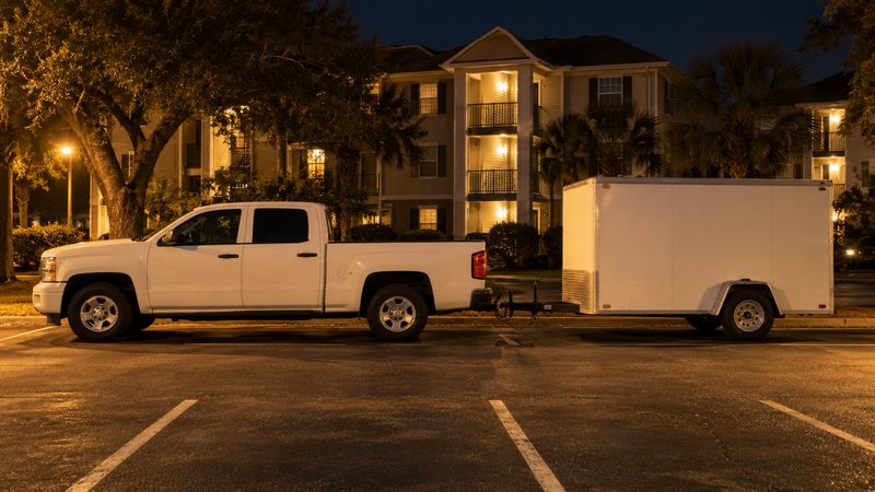 Pickup truck with an enclosed utility trailer parked at an apartment complex at night